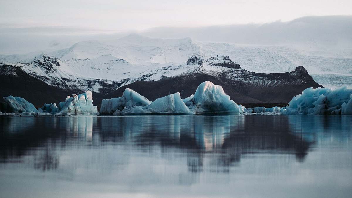 nature reflection of snow mountain on body of water under white sky outdoors