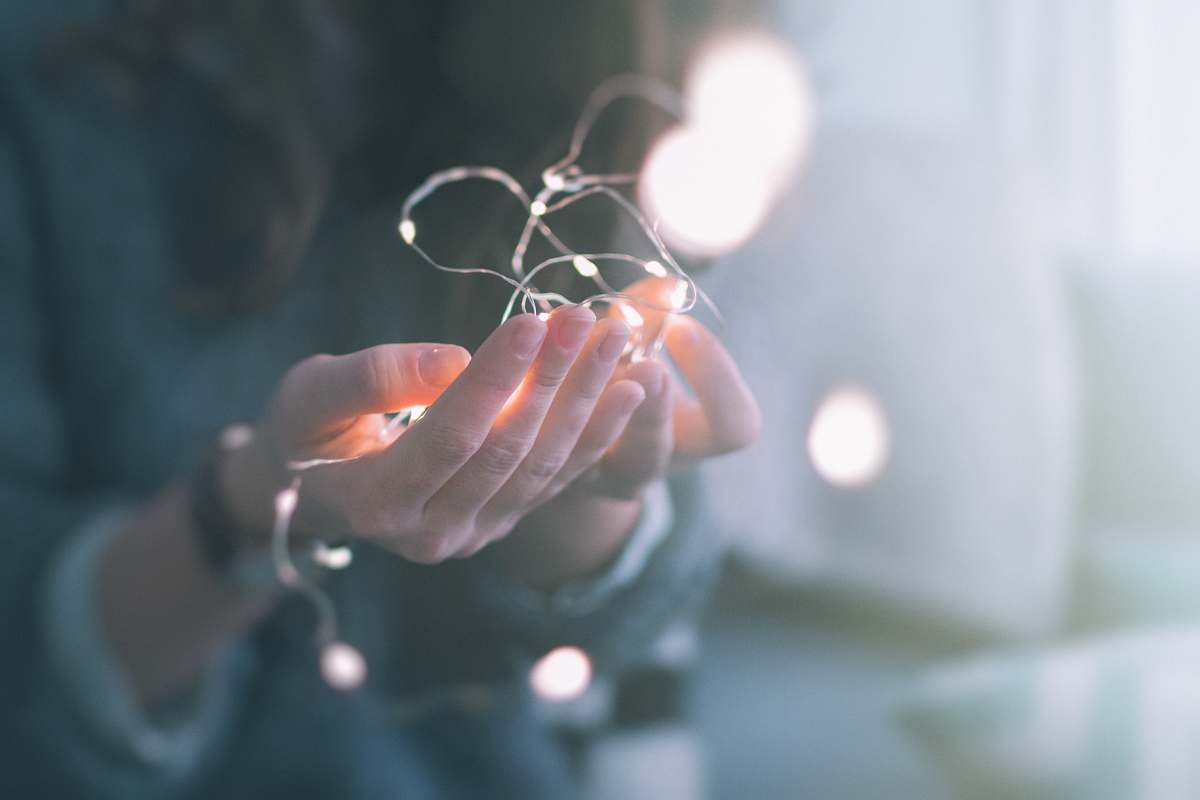 hands shallow focus photograph of person holding string lights christmas