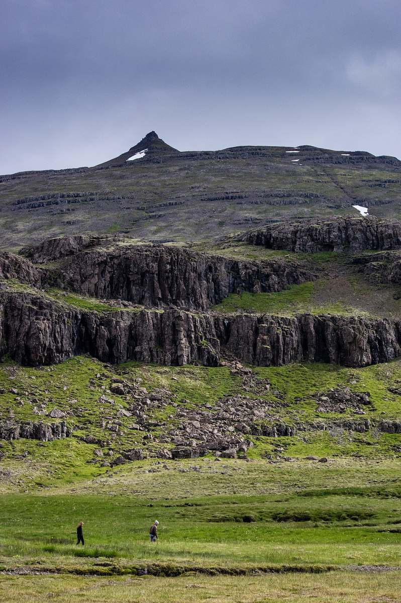 iceland two person walking on green grass field with mountain outdoors