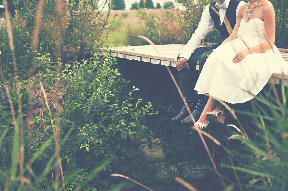 human couple sitting on wooden bridge wedding