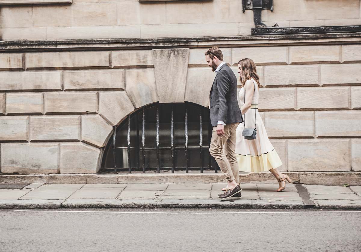 person man and woman walking beside a road during daytime human