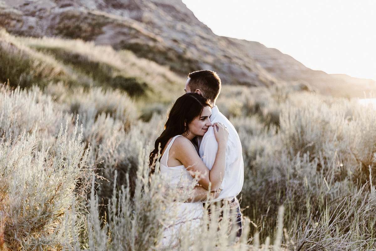 person man hugging woman near mountain grass
