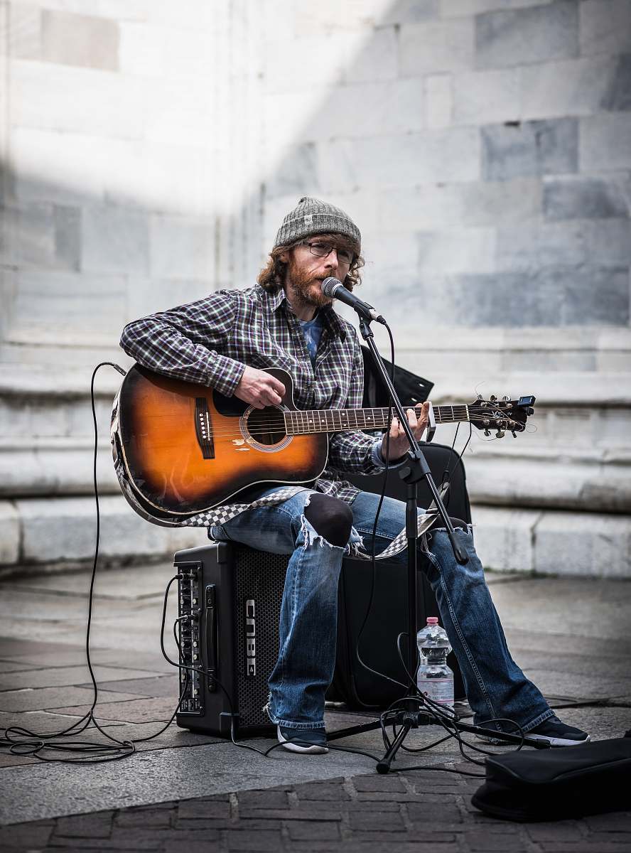 music man performing guitar while singing front of stage musician