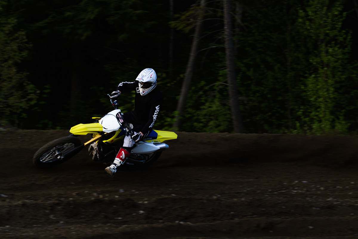 human man ridding yellow and white motocross dirt bike back