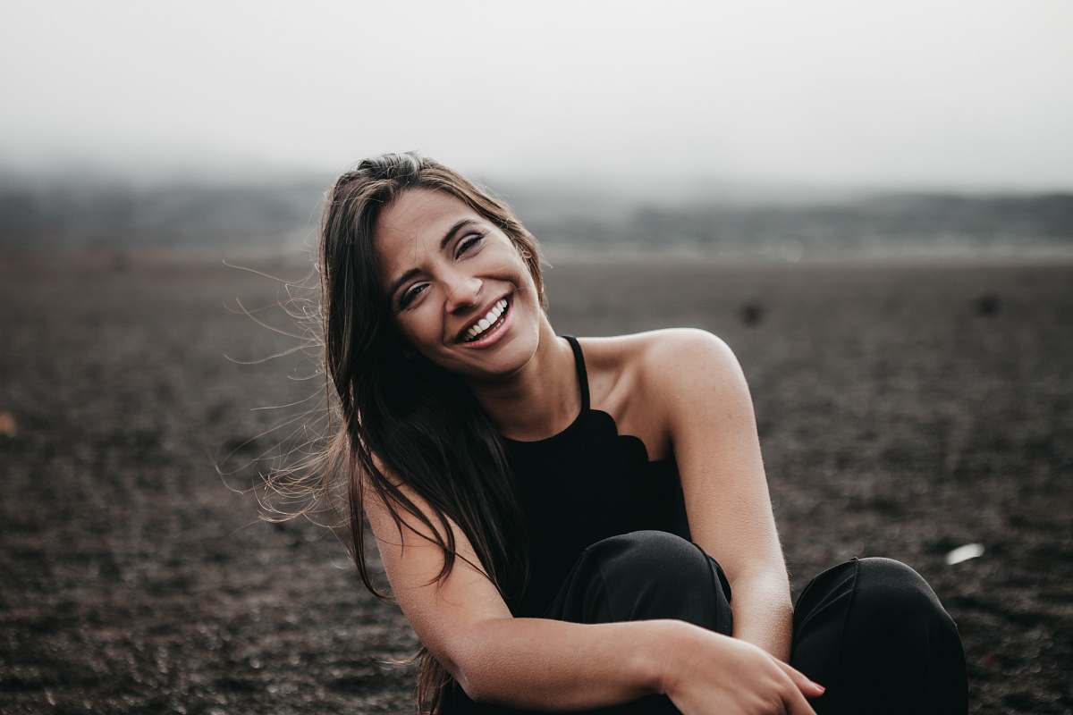 person woman laughing while sitting on ground woman