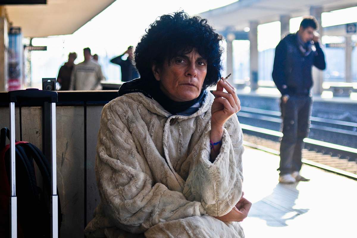 human man sitting and smoking at the train station hair