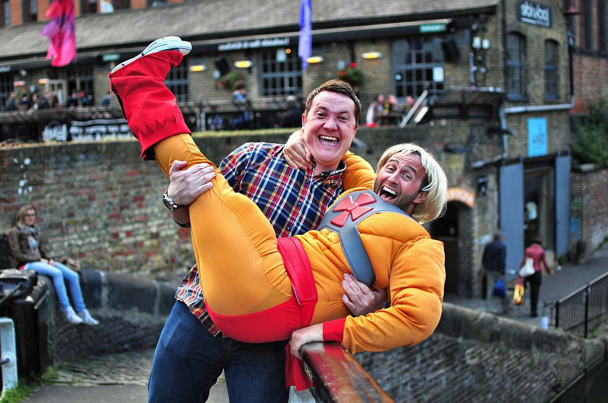 people man standing on gray bridge while carrying a man during daytime human