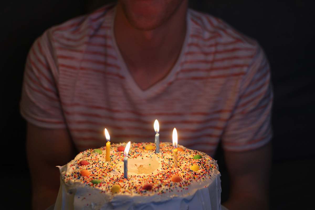 cake person holding white icing-covered cake dessert