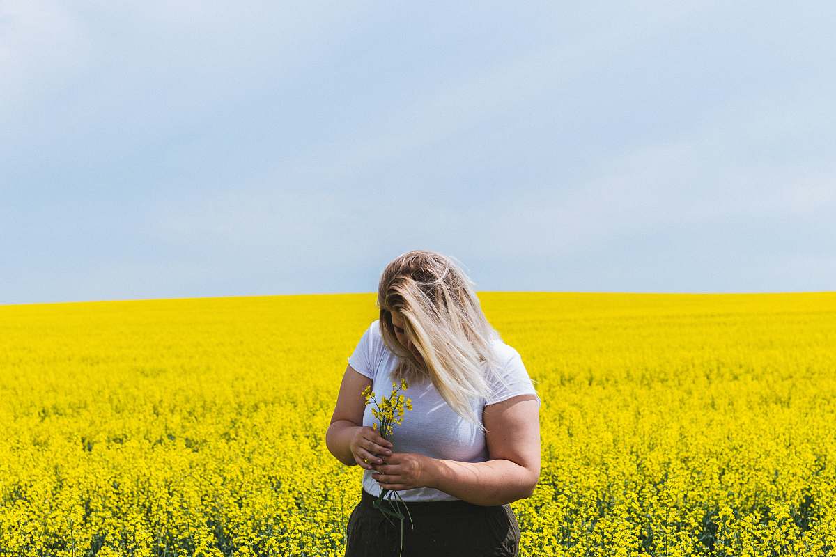 field woman standing and holding flowers on flower field girl