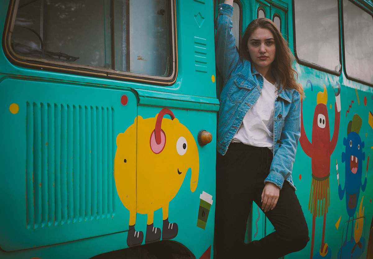  woman standing beside teal bus 
