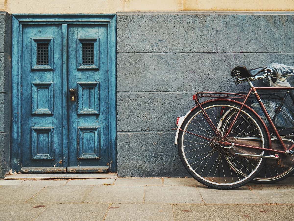 door minimalist photography of parked bicycle near blue door bike