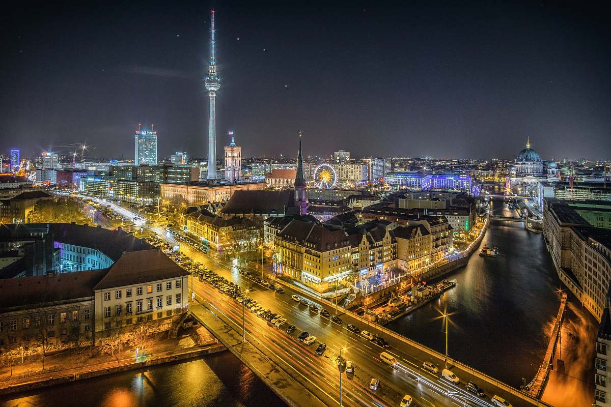 berlin time-lapse photography of vehicle at the road in between the building at nighttime aerial photography building