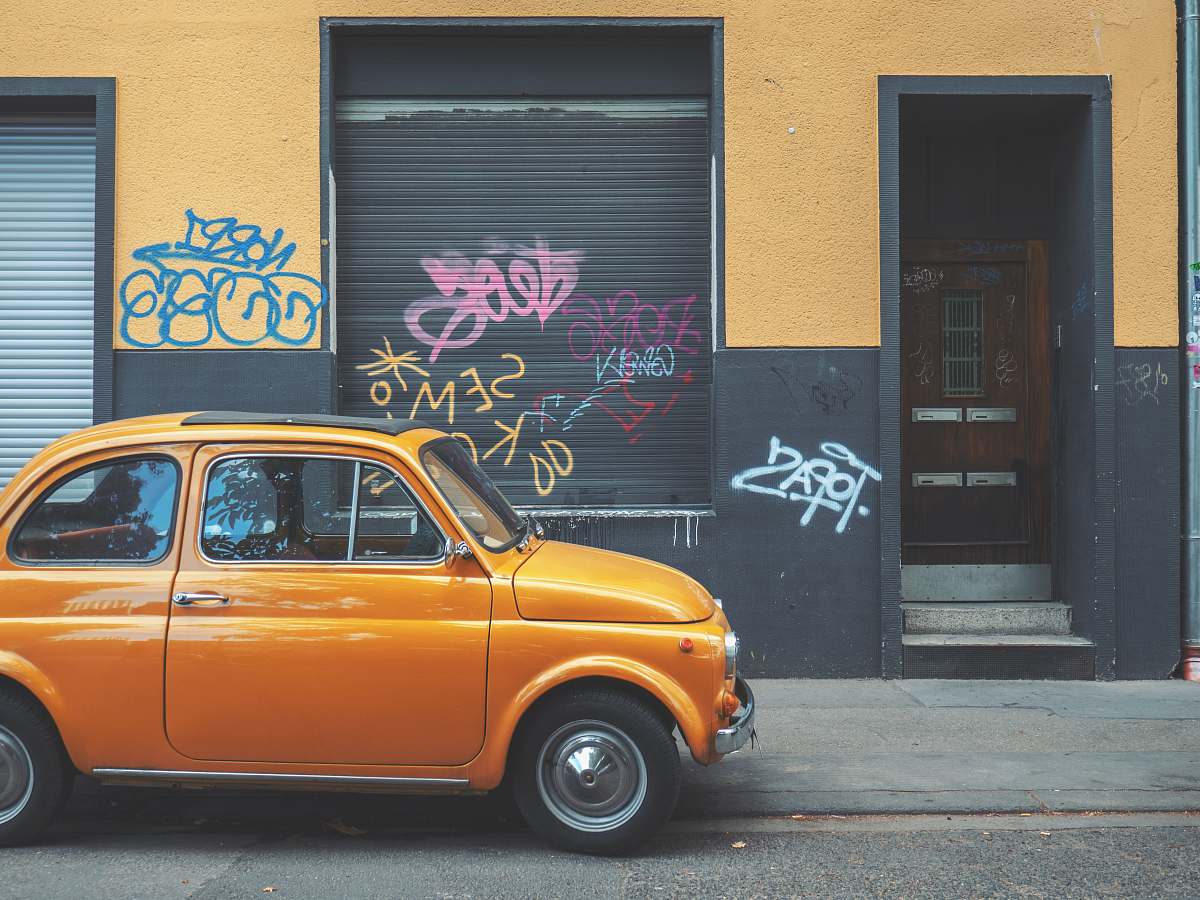 automobile yellow car near grey shutter door car