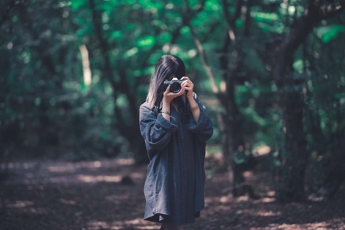 clothing woman using camera near trees coat