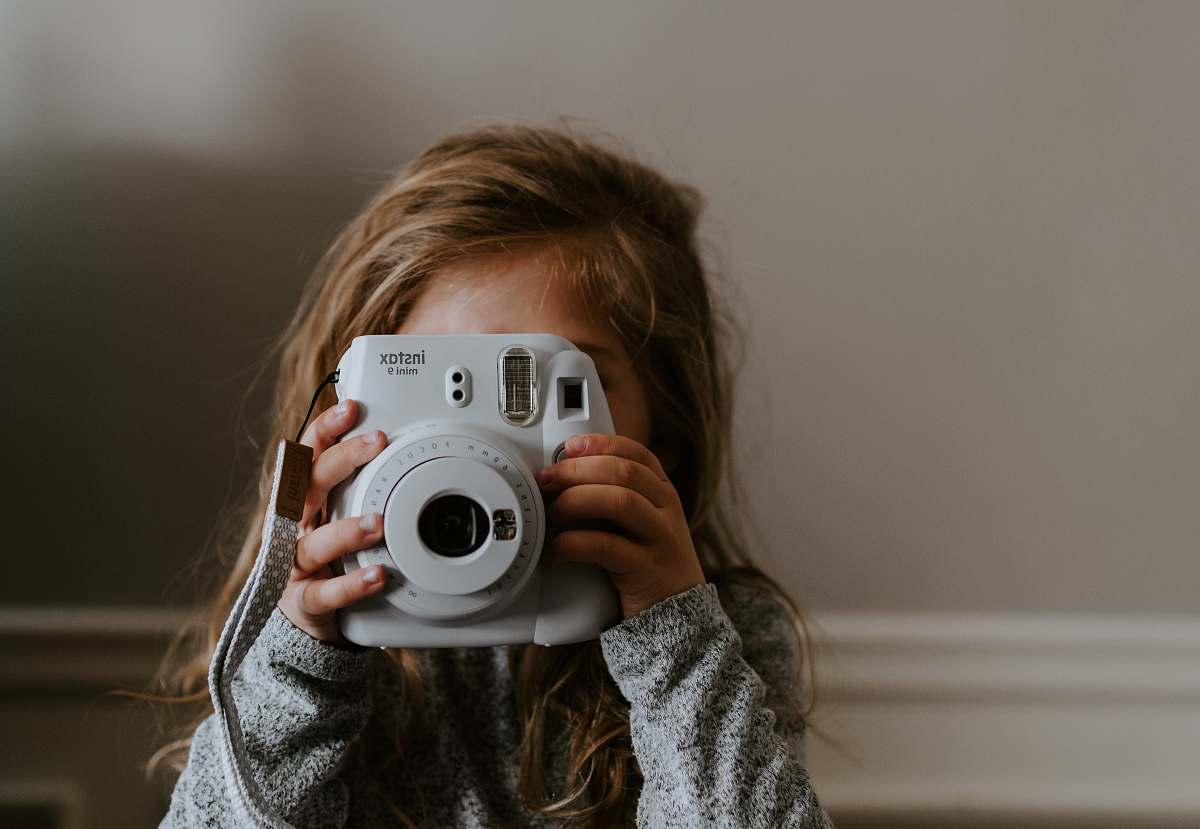 person girl taking a picture using instant camera human