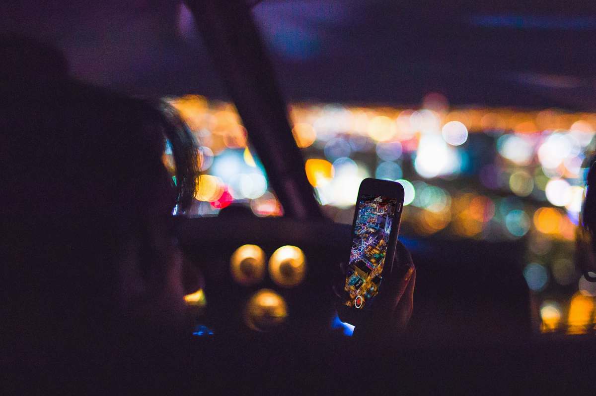 lights person using Android smartphone inside car aerial view