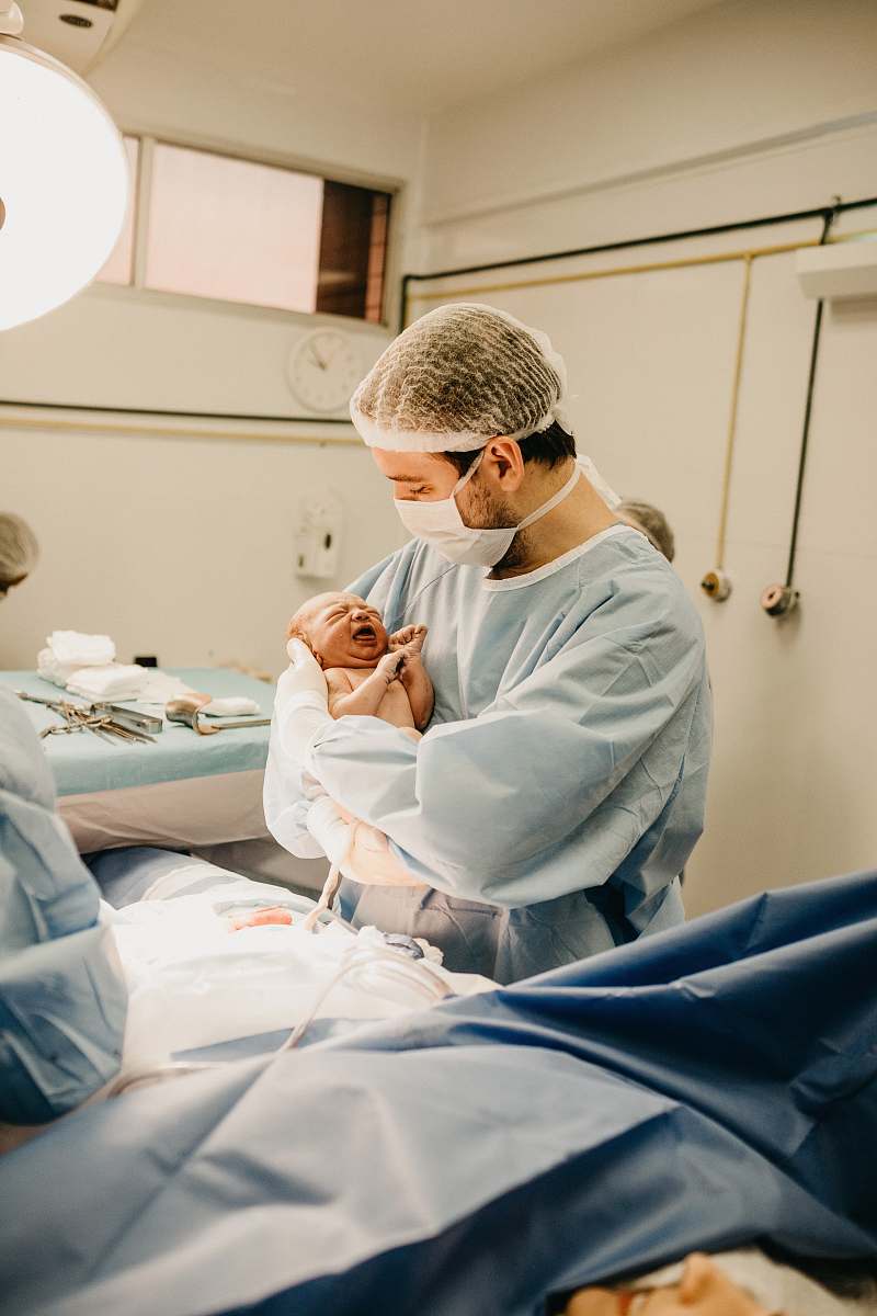 hospital man in lab suit and mask carrying newborn baby human
