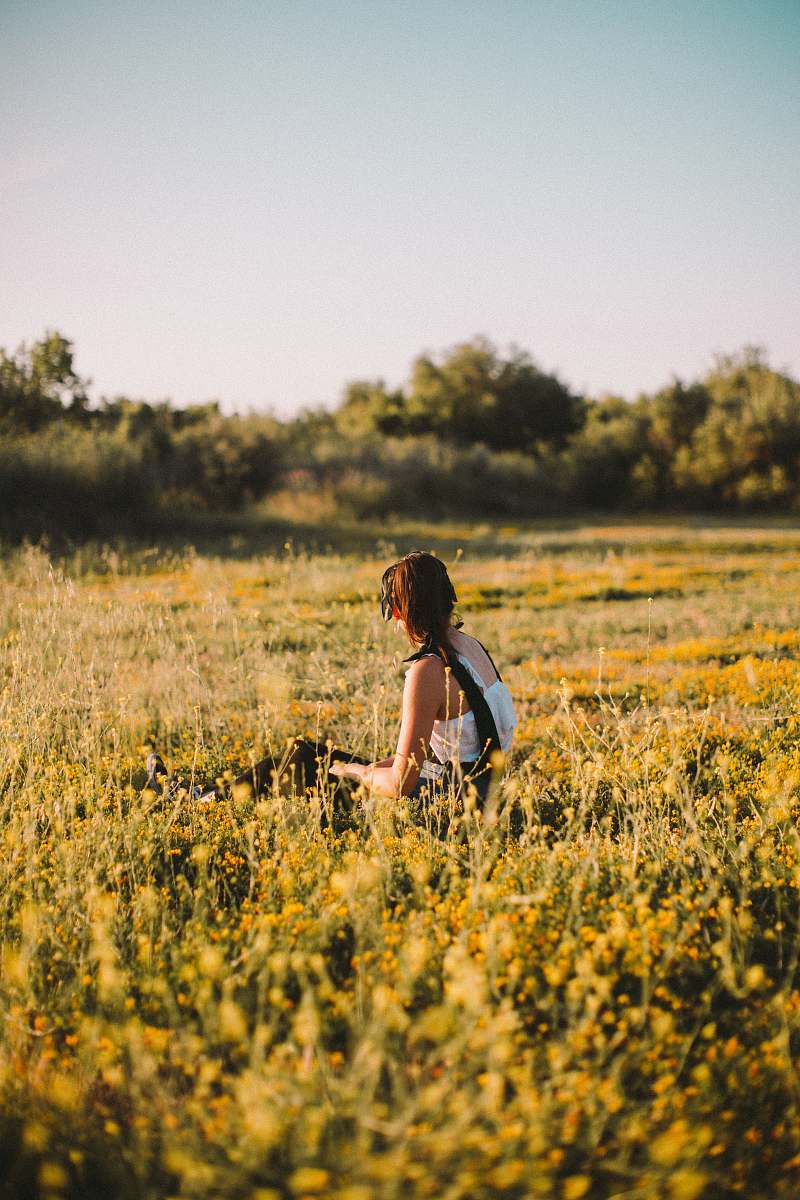 grassland woman sitting on yellow-petaled flowers outdoors