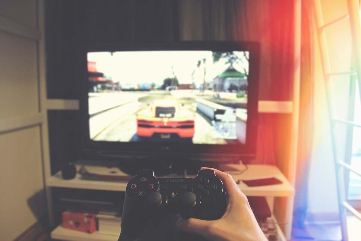 apartment person holding Sony PS3 controller in front of flat screen monitor tv