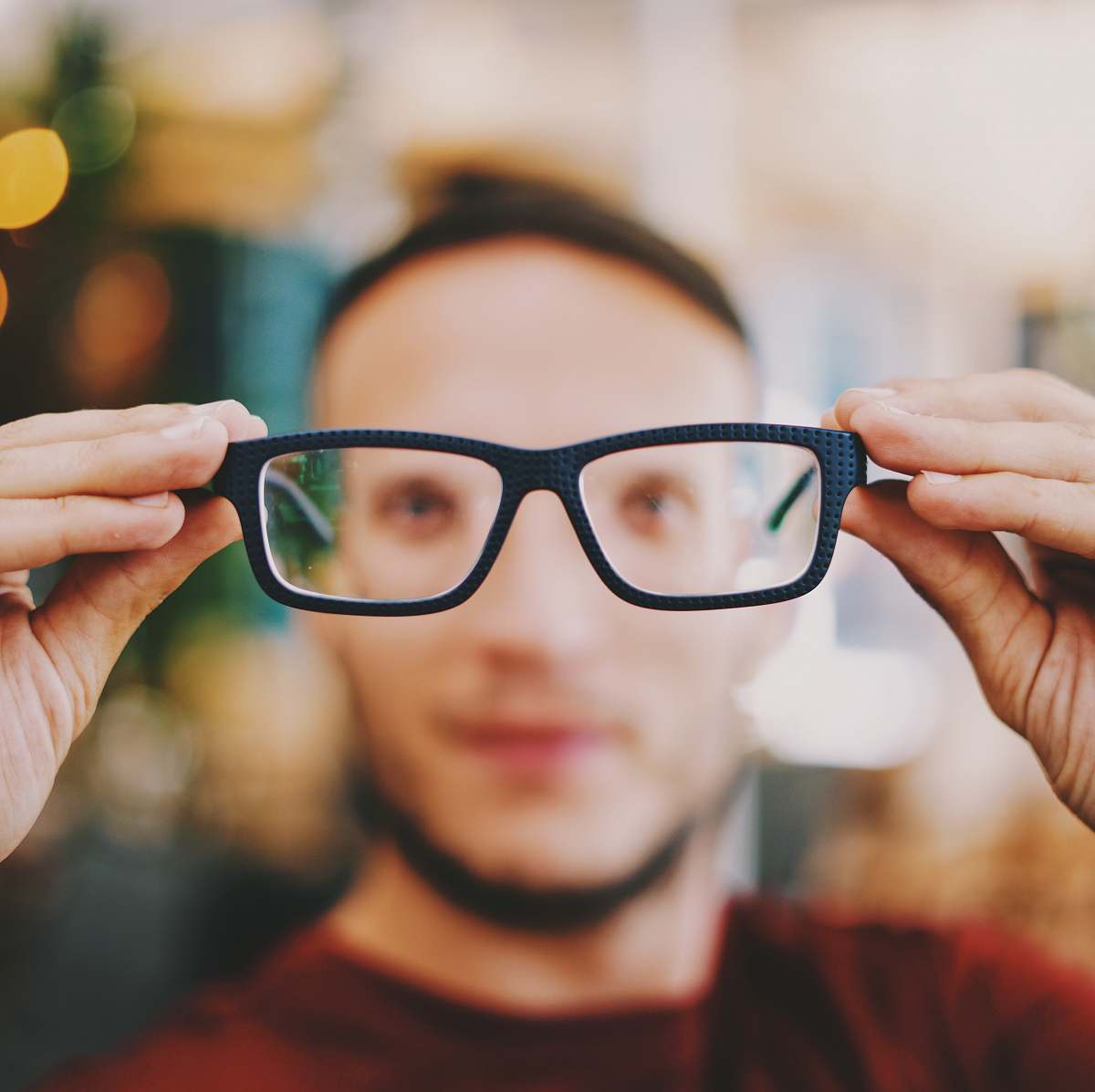 human person holding eyeglasses with black frames person