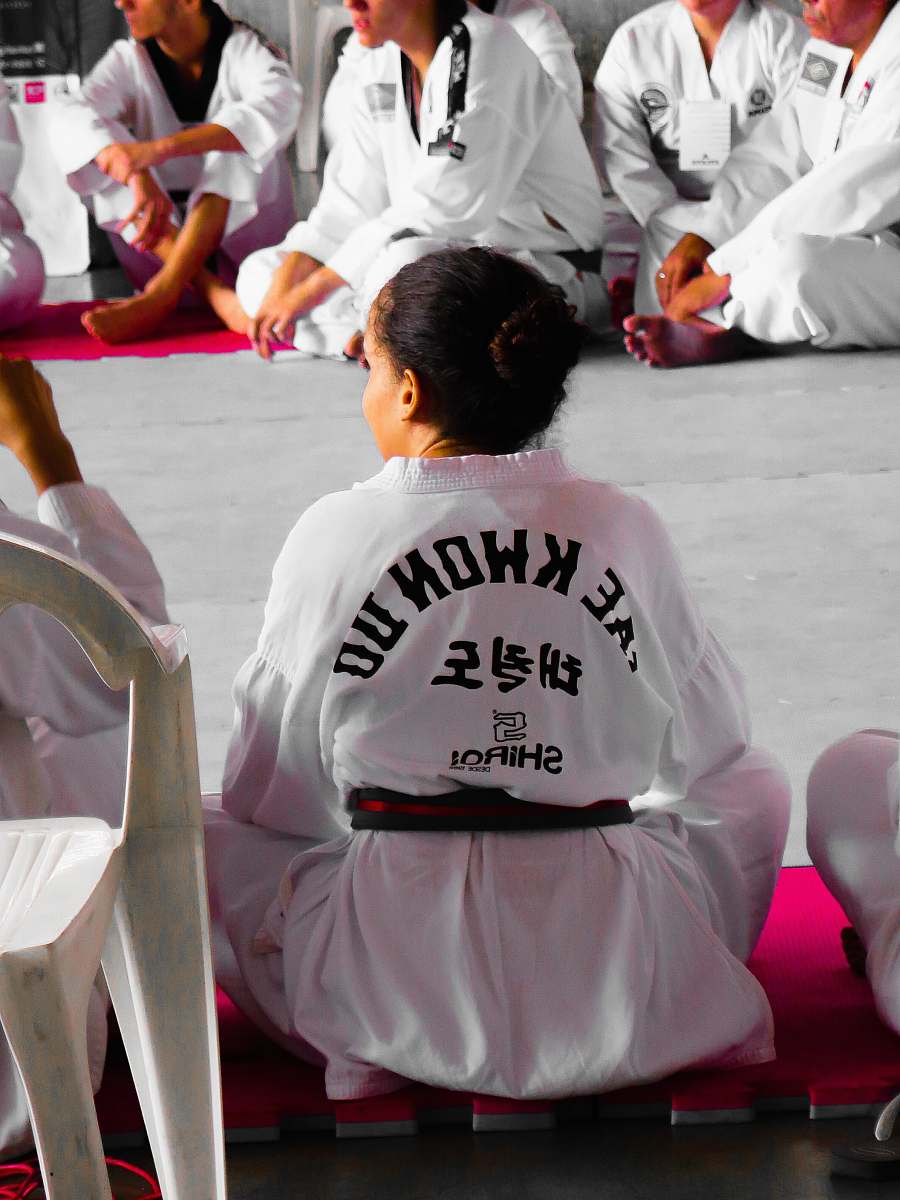 person girl wearing karate gi sitting on pink puzzle mat people
