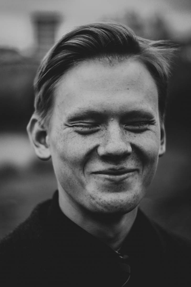 person grayscale photo of smiling man black-and-white