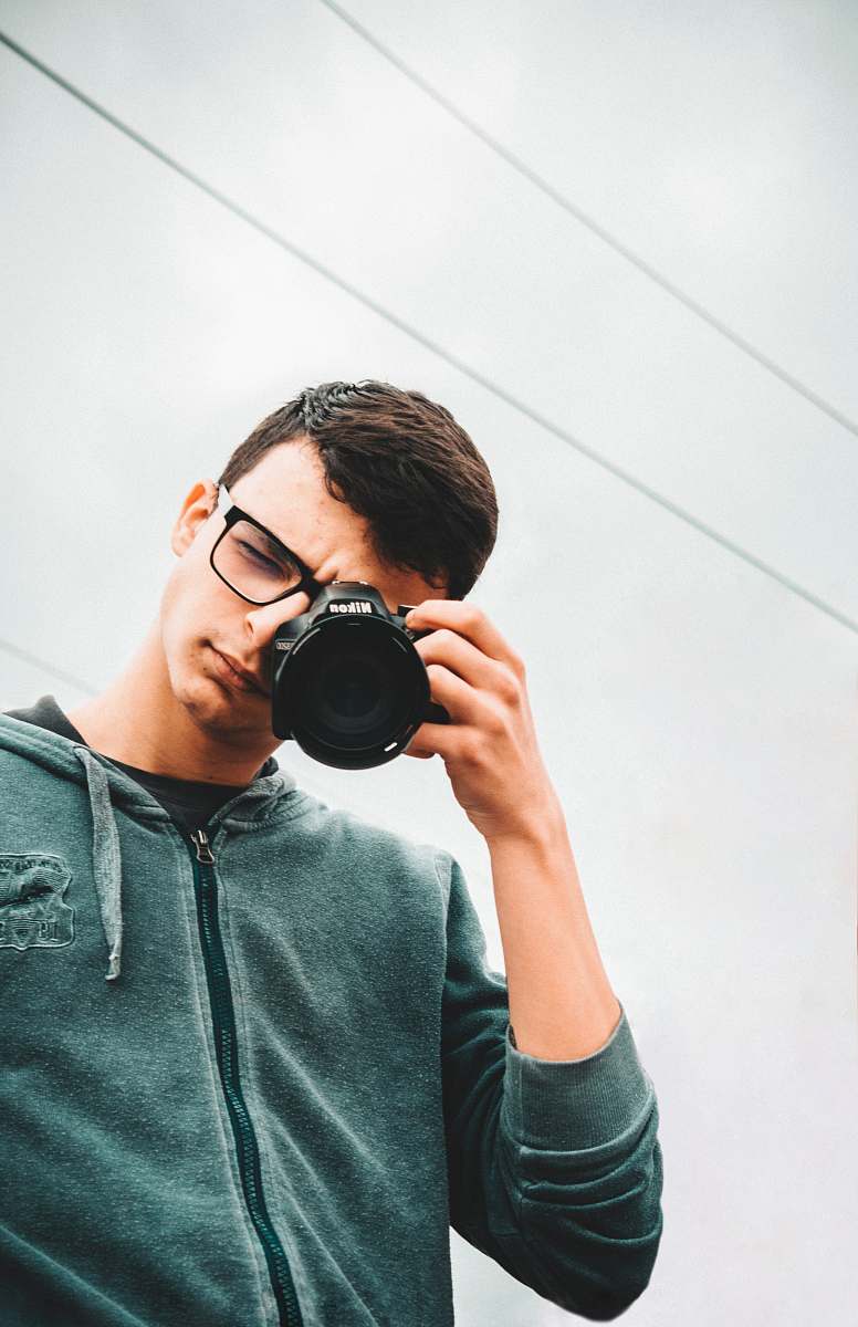 person man in green hoodie aiming camera photo