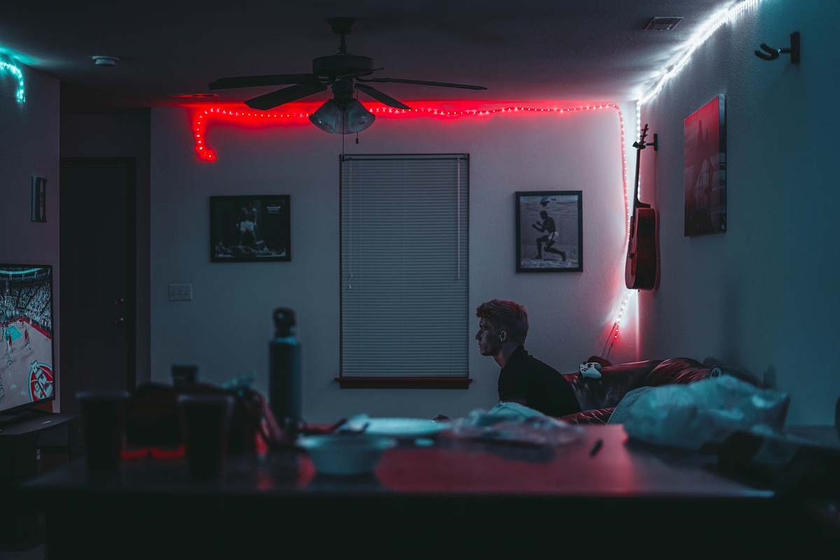 man man sitting inside room near window blinds with lights turned on room