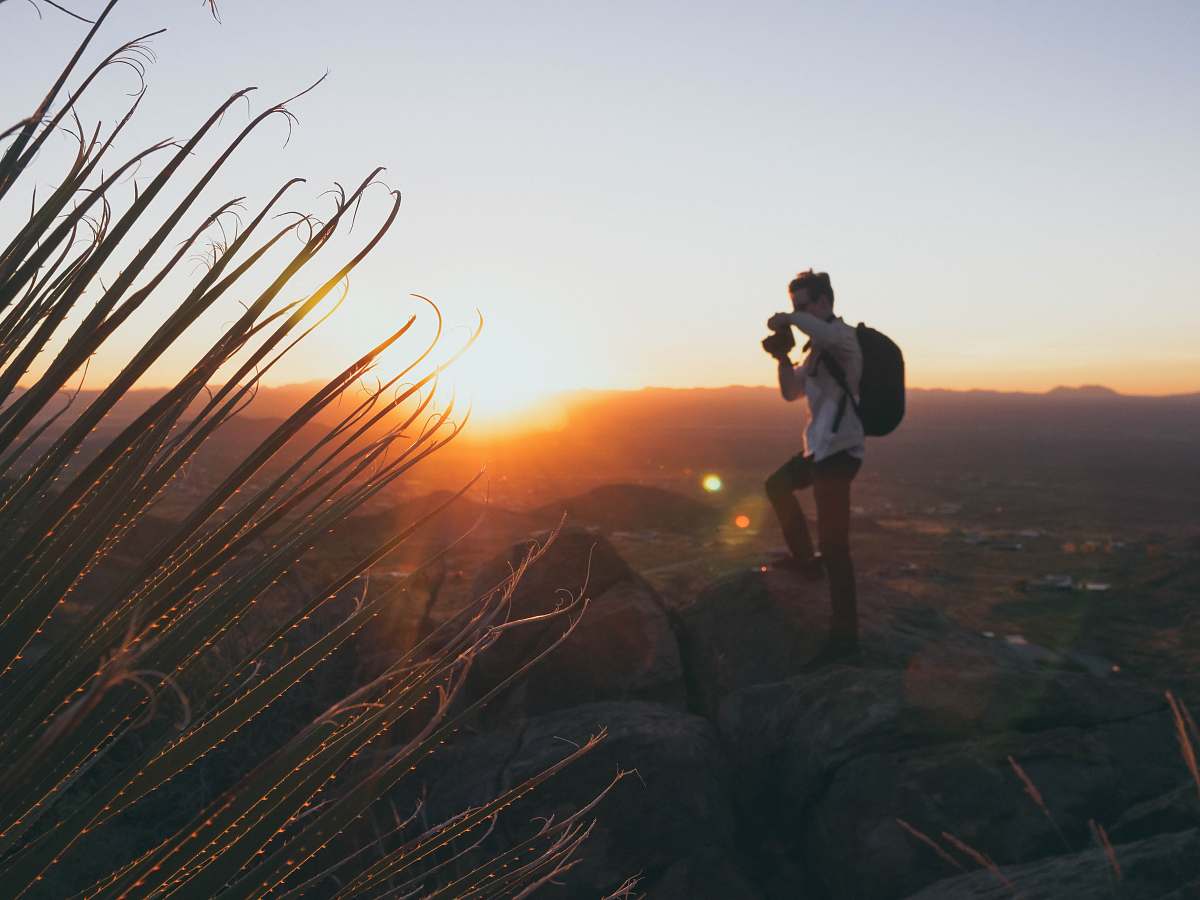 person man standing on cliff during golden hour photographer