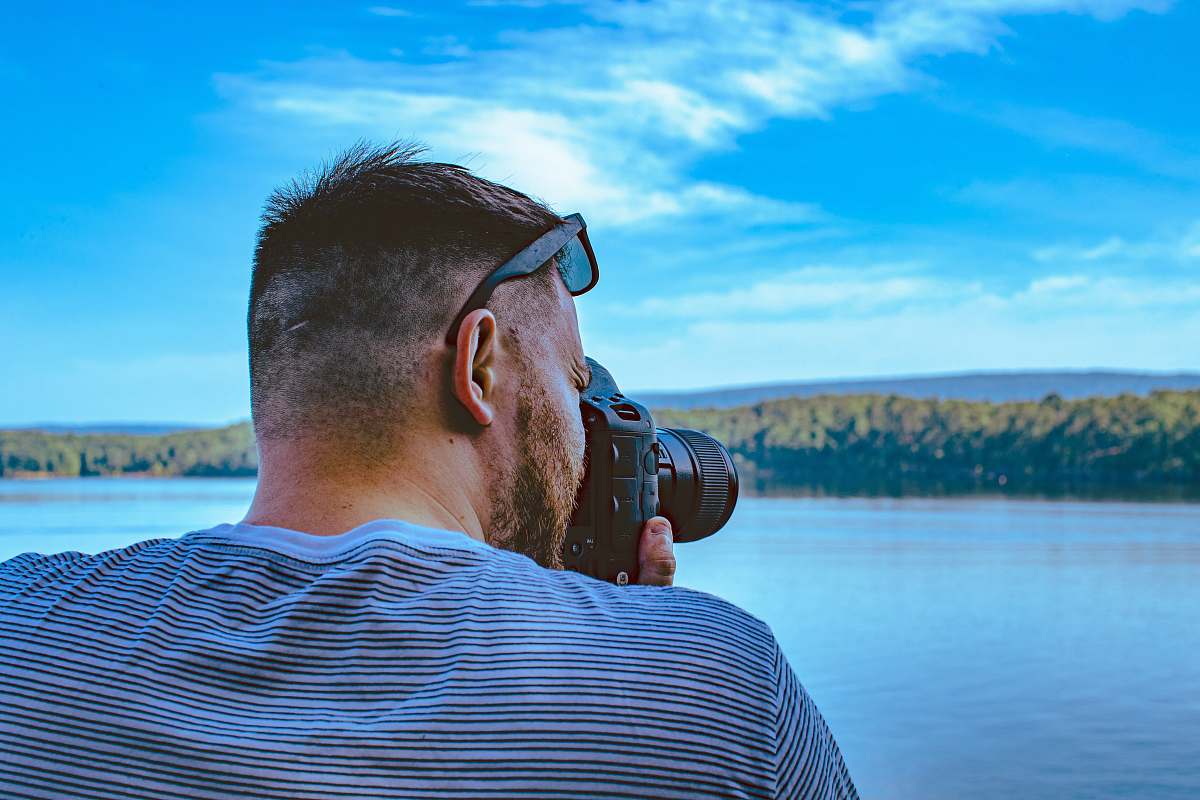person man taking photo of calm sea under blue and white skies arkansas