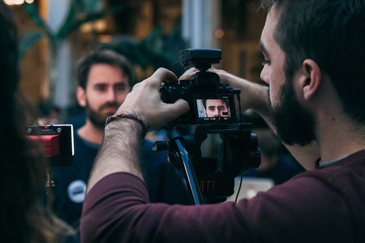 person man taking video of standing man wearing black crew-neck top camera