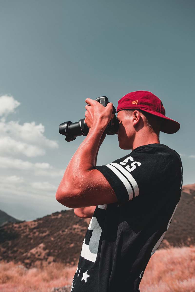 person man using DSLR camera outdoors during daytime apparel