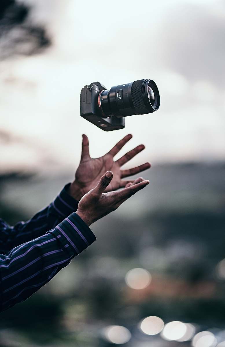 person man wearing blue dress shirt catching black DSLR camera camera
