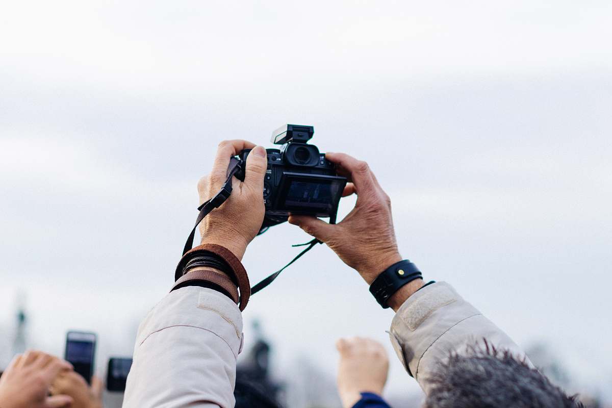 person person holding black DSLR camera taking picture during daytime camera
