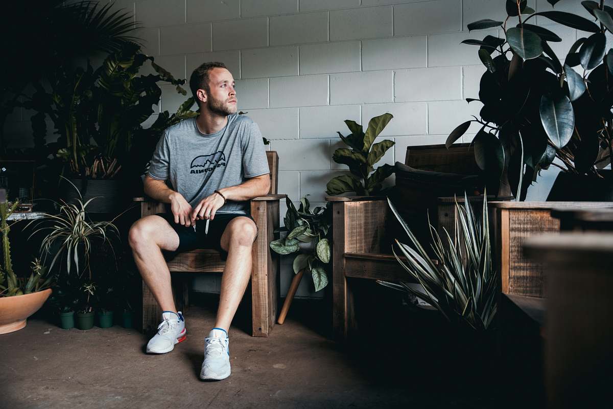 people seated man between potted plants in front of while wall plant