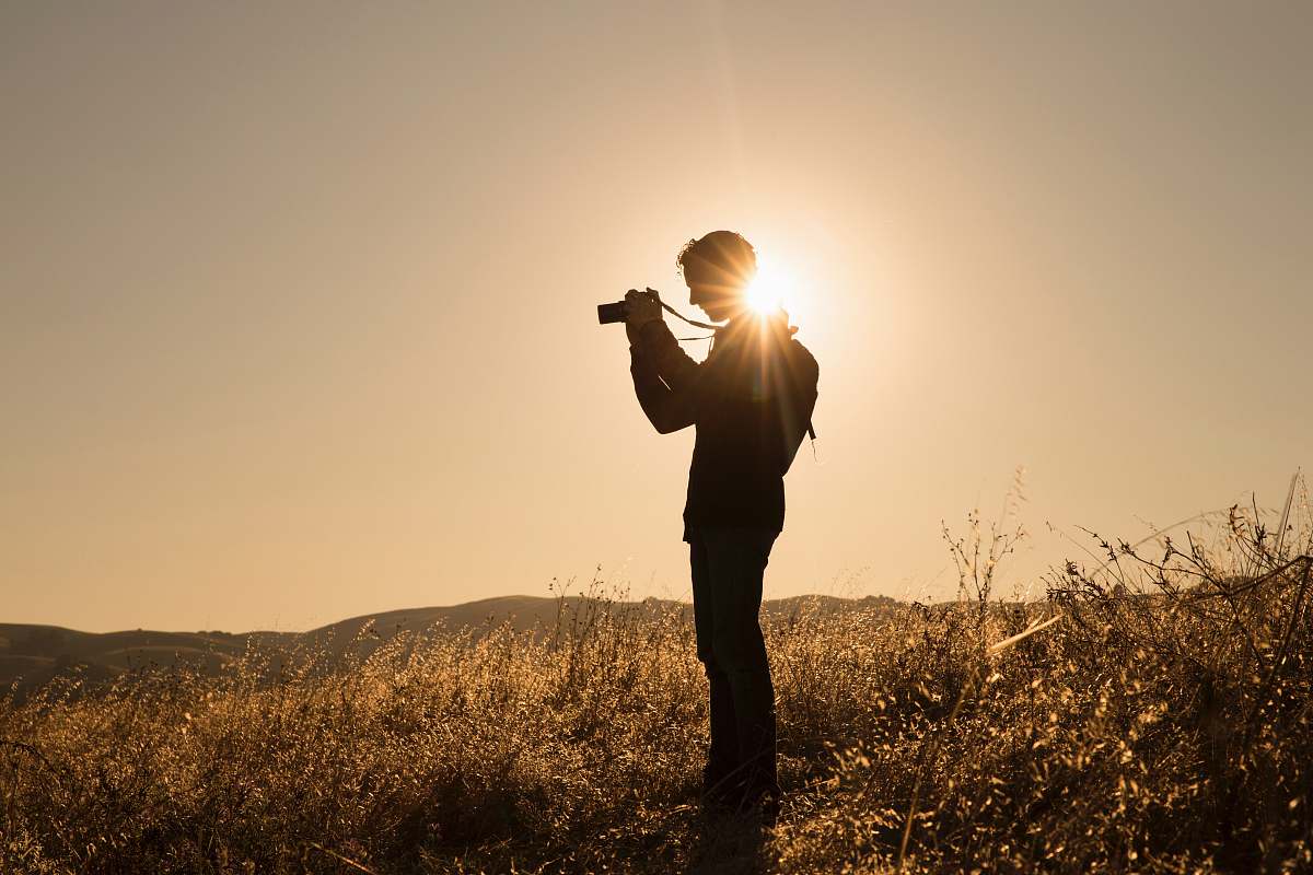 person silhouette of person holding camera on brown fields during daytime photography
