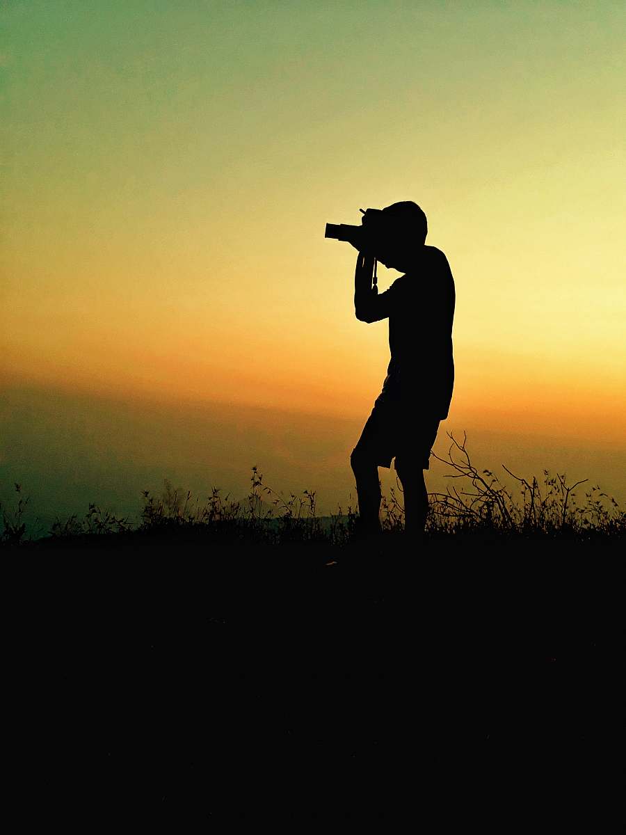 person silhouette photography of man taking picture using camera photo