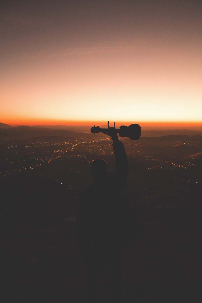 person silhouette photography of person holding guitar photo