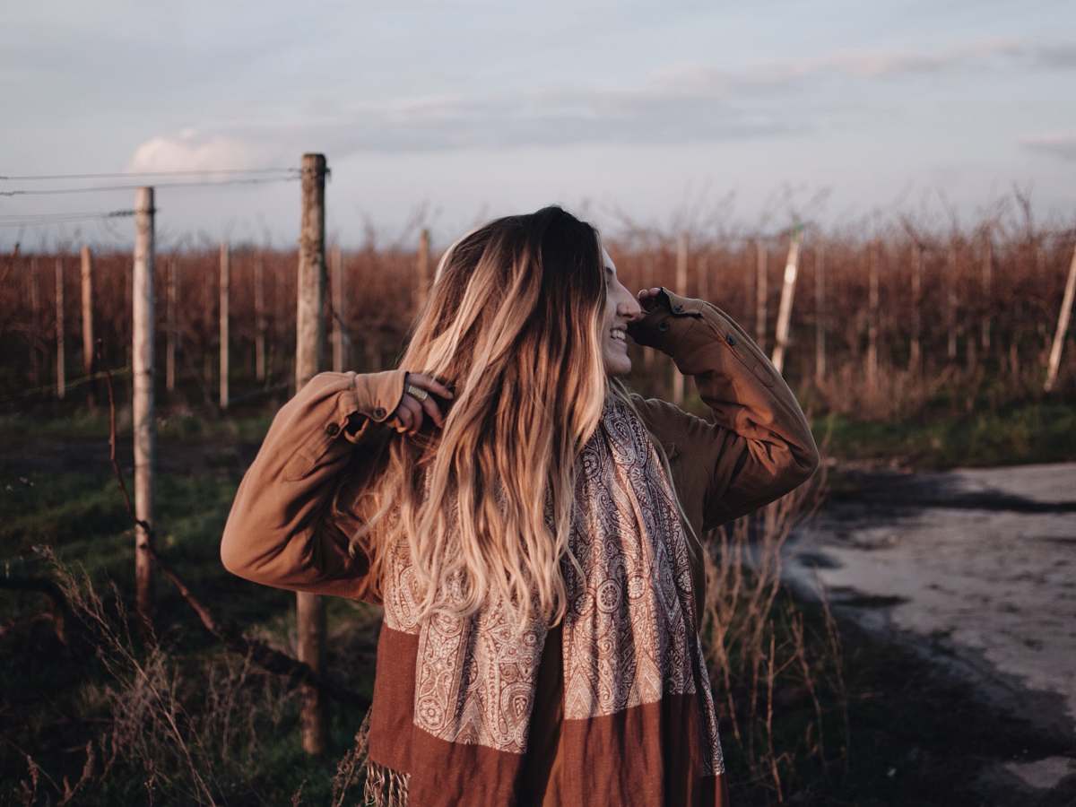 person smiling woman in brown jacket raising both hands during daytime photo