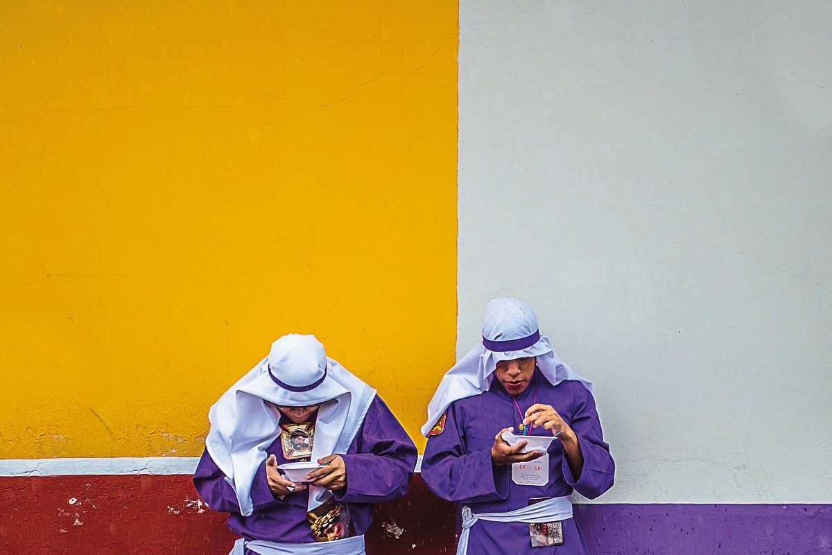 person two standing men wearing purple long-sleeved top leaning on white, yellow, purple, and red painted wall people