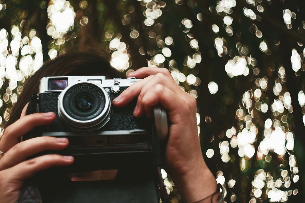 camera woman holding black camera electronics