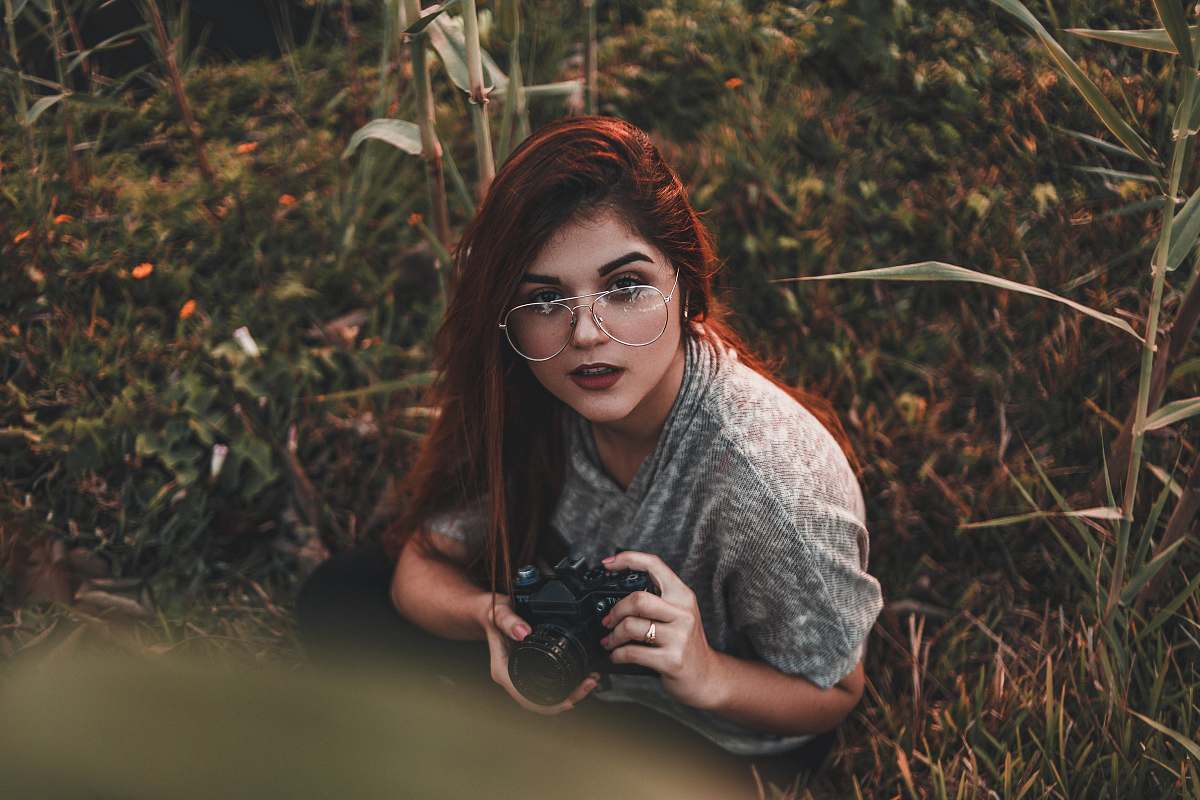 person woman holding camera while sitting on grass camera