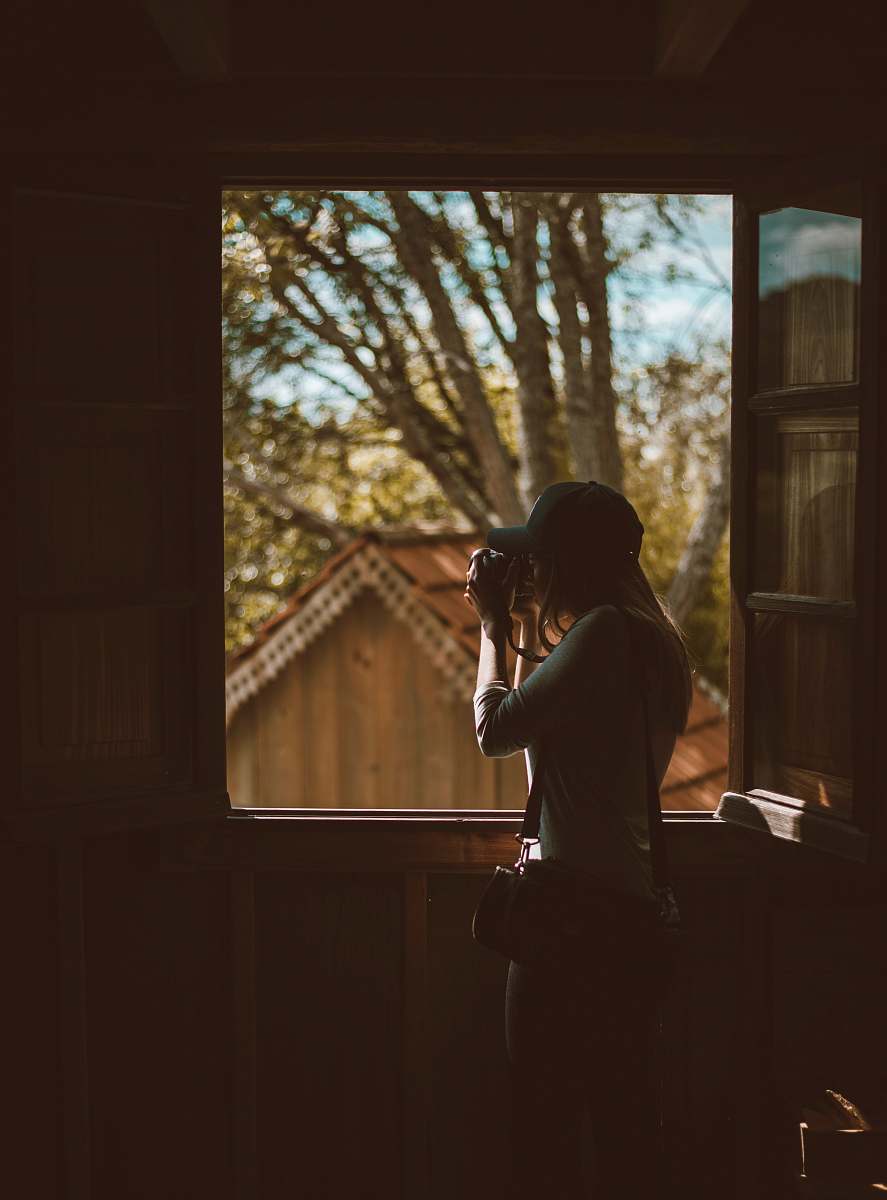 person woman taking photo outside window photo
