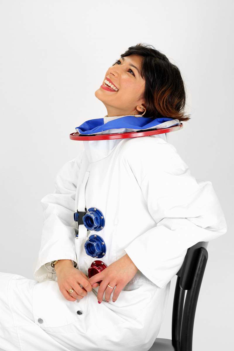 person woman wearing astronaut suit smiling while sitting on chair and looking up people