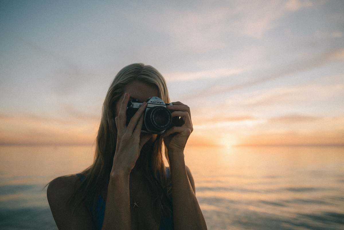person woman wearing blue top holding gray DSLR camera camera