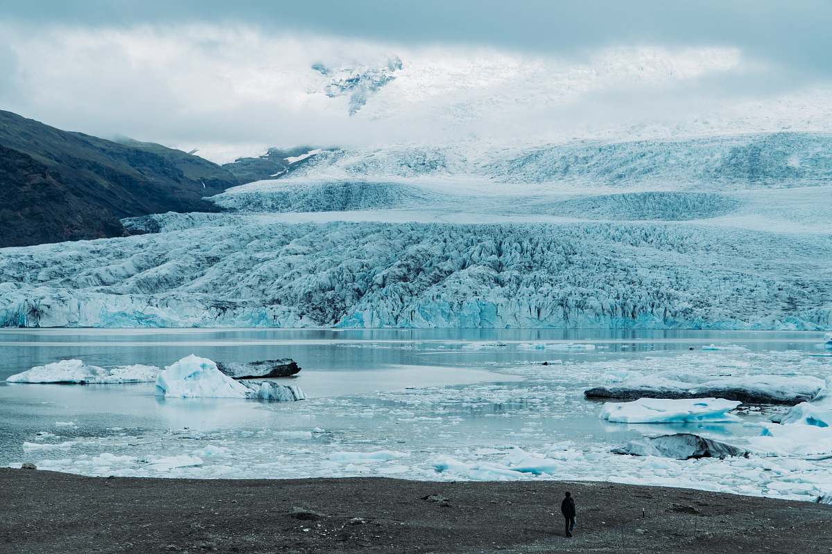 nature person standing beside snowy plains and frozen lake outdoors