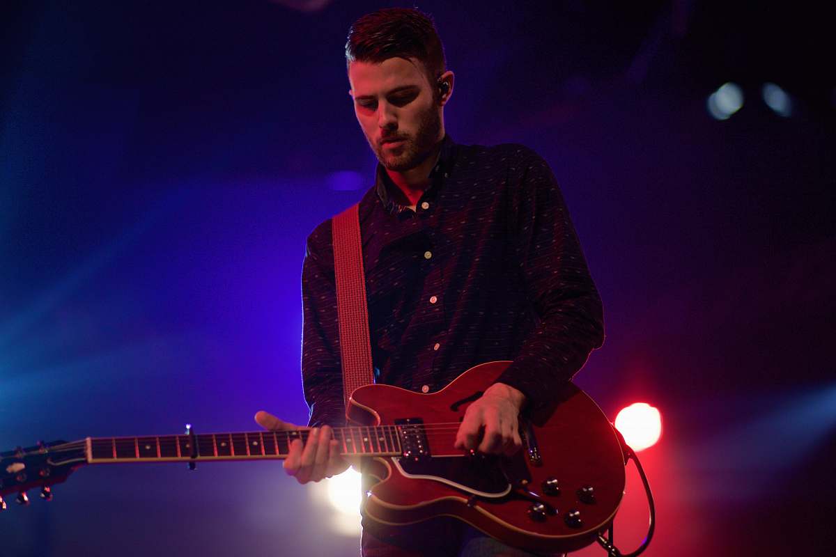 person man playing black electric guitar guitar