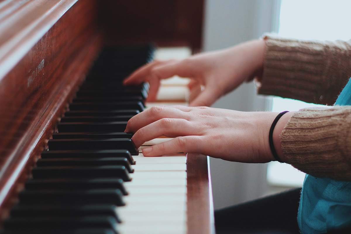 piano person wearing brown sweater playing piano pianist