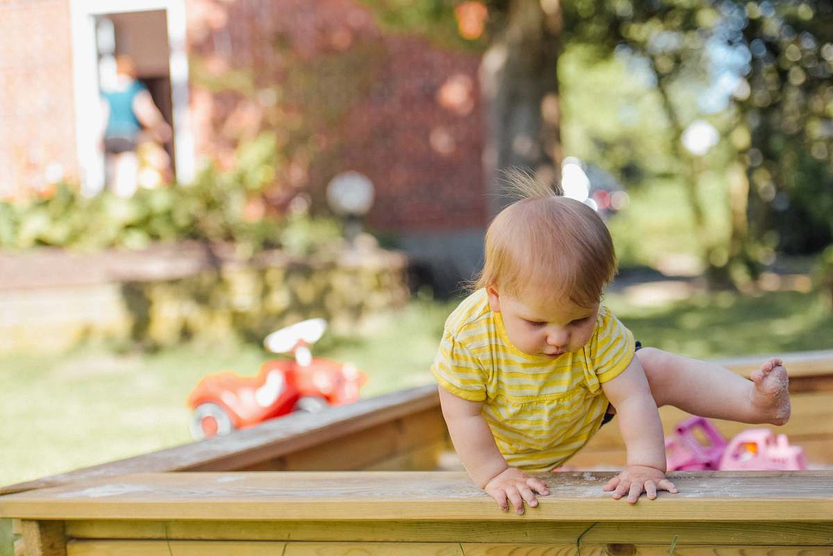 person baby trying to get out of his crib kid