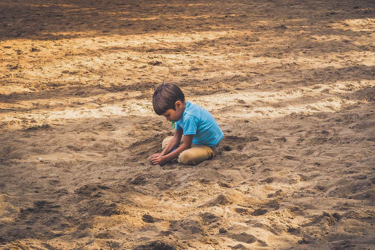 sand boy playing on sand during daytime outdoors